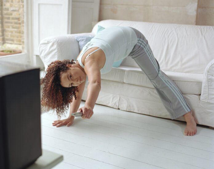 A young lady doing exercise while watching tv